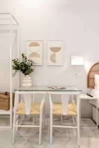 een witte tafel met twee stoelen en een vaas erop bij ISG Apartments Cuna 10 in Sevilla