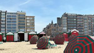 a beach with umbrellas in the sand in front of buildings at Louis-Gabriël in De Panne