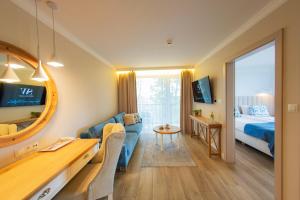 ウストカにあるHotel Szerokie Wody Sea & Sand Ustkaのソファとベッド付きのホテルルーム