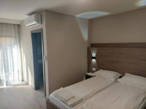 1 dormitorio con 1 cama con cabecero y ventana en Pensiunea Normandia, en Timisoara