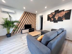 uma sala de estar com um sofá azul e uma televisão em Le Moderna Cocooning - Climatisé em Coulounieix-Chamiers