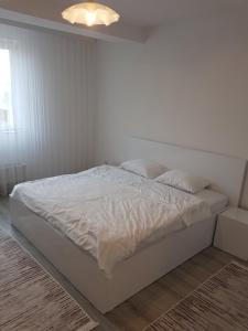 uma cama branca num quarto com uma parede branca em Banesa ne FushKosovë em Pristina