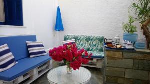 - un canapé bleu et une table fleurie sur la terrasse dans l'établissement Small traditiional home near the shops and restaurants in Korissia, Kea, à Ioulída