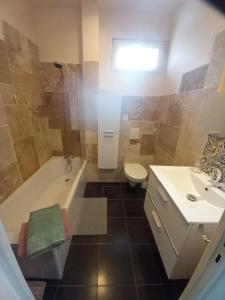 a bathroom with a tub and a toilet and a sink at Aix-les-bains centre, 2 ch, 4 pers, climatisé in Aix-les-Bains +14 photos