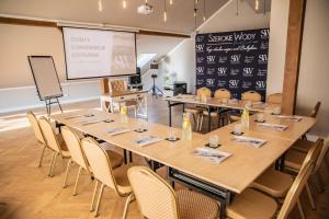 une salle de réunion avec des tables et des chaises et un écran de projection dans l'établissement Szerokie Wody Sea & Sand Ustka, à Ustka