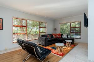 uma sala de estar com um sofá, cadeiras e janelas em Hout Bay Hilltop em Hout Bay