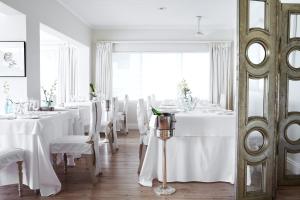 un comedor con mesas blancas y sillas blancas en Leisure Isle Lodge, en Knysna