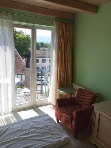 ein Schlafzimmer mit einem Bett, einem Stuhl und einem Fenster in der Unterkunft La Strada in Murnau am Staffelsee