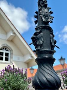 a black pole in front of a house with purple flowers at Éllő Residence in Veszprém