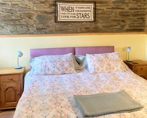 a bed with a purple headboard and pillows on it at The Old Stables Brongest in Troedyraur