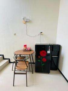 ein Tisch und ein schwarzer Kühlschrank mit einer darauf gemalten roten Rose in der Unterkunft Villa Tanjung Alam Batu Syariah in Tlekung
