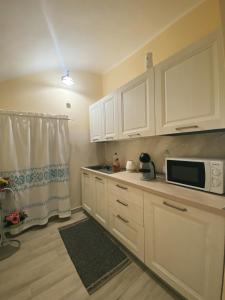 a kitchen with white cabinets and a microwave at Tra i due ponti in Bosa
