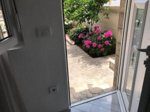 an open door with pink flowers in a yard at Apartment K2 in Radanovići