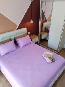 a bedroom with a large bed with purple sheets and mirrors at theasis1 in Neos Marmaras