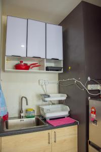 cocina con fregadero y armarios blancos en Homestay at Menara U, en Shah Alam
