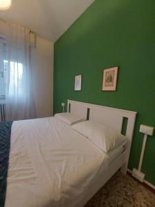 a bedroom with a white bed with a green wall at Sauro 43 in Pisa