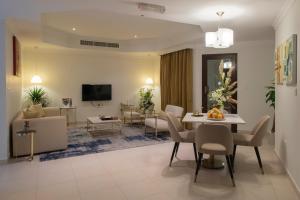 een woonkamer met een tafel en stoelen bij Corp Hotel Apartments and Spa in Doha