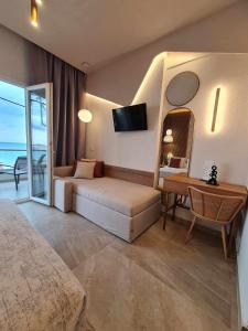 a bedroom with a couch and a table and a mirror at Anna Beach Suites in Limenaria