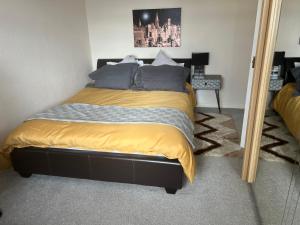 1 dormitorio con 1 cama con sábanas amarillas y espejo en Cozy 3 bedroom bungalow in rural location en Ashwell
