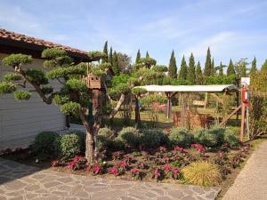 un jardín con un árbol y flores en un patio en Comfortable campsite-chalet G14 Tuscany near sea en Viareggio