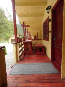 un porche de una casa con mesas de picnic en Casutele Likas en Lacu Rosu