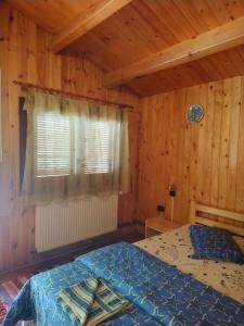 um quarto com uma cama num quarto de madeira em Casutele Likas em Lacul Roșu