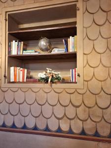 un estante de libros con libros y flores. en Casa Barattini, en Zocchetta