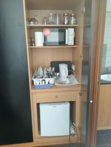 uma cozinha com micro-ondas e uma prateleira com utensílios em O Cantinho do Arnaldo em Viana do Castelo