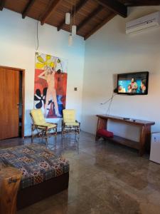 uma sala de estar com uma televisão e uma mesa e cadeiras em Brisa da Serra Hotel Pousada Pirenopolis em Pirenópolis