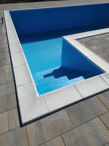 een zwembad met blauw water en een witte stoeprand bij Villa Ella in Ljubuški