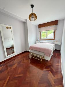 1 dormitorio con cama, ventana y espejo en Apartamento a 5 minutos del casco histórico, en Viveiro