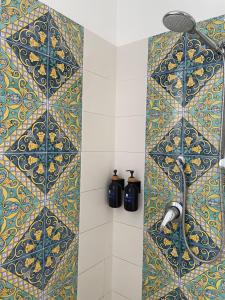 y baño con ducha de azulejos azules y amarillos. en Taormina Rooms Panoramic Apartments en Taormina