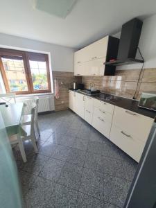 a kitchen with white cabinets and a table and a dining room at Holiday House in Krynica Morska