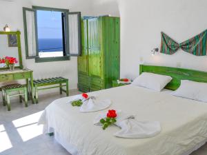 een slaapkamer met een groot wit bed met rode bloemen erop bij Hotel Finiki View in Foiníkion
