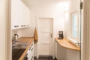 uma cozinha com armários brancos e um lavatório em Modernes Altstadt Apartment em Bad Belzig