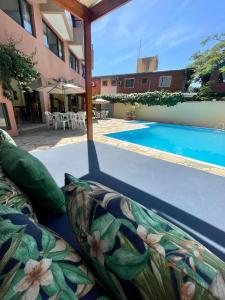 uma vista para uma piscina com um sofá ao lado de um edifício em Hotel Ponta das Toninhas em Ubatuba