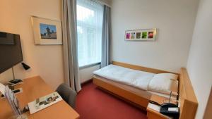 シャフハウゼンにあるホテル プロムナードのベッドとデスクが備わる小さな客室です。