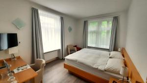 a bedroom with a bed and a desk and two windows at Hotel Promenade in Schaffhausen