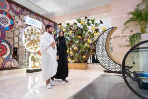 a man and a woman walking in a store lobby at Swissotel Makkah in Makkah