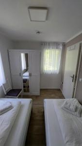 a white bedroom with two beds and a mirror at Ferienbungalows am Wolziger See in Heidesee