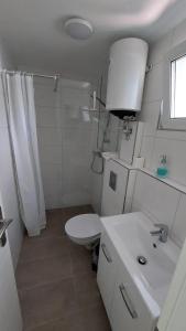 a white bathroom with a toilet and a sink at Ferienbungalows am Wolziger See in Heidesee