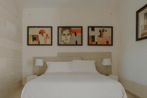 1 dormitorio con 1 cama blanca y 4 cuadros en la pared en Villa Patrizia Salento Art & Room en Porto Cesareo