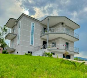 a white building on a hill with green grass at Bujtina Amar in Lazarat