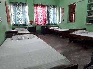 Habitación con 3 camas en una habitación con ventanas en Pushpak Guest House Boys, Near DumDum metro Station, en kolkata