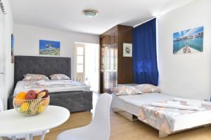 a bedroom with two beds and a table with a bowl of fruit at Apartment Lucky in Budva