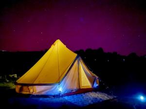 Tienda amarilla iluminada por la noche en Tente Lodge TIPI A 1H de Nice CLAIR DE LUNE, en Bézaudun-les-Alpes