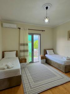 a bedroom with two beds and a sliding glass door at Bujtina Amar in Lazarat