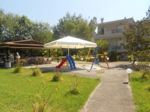 a playground with an umbrella and a swing set at Elia Apartments in Oreoi