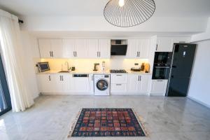 a kitchen with white cabinets and a black refrigerator at Oasis Family-Friendly Luxury Villa Fethiye Oludeniz by Sunworld Villas in Fethiye