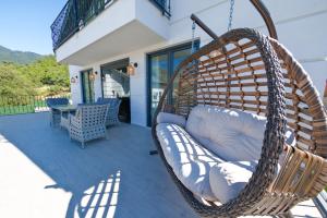 a wicker swing chair on a porch with a table at Oasis Family-Friendly Luxury Villa Fethiye Oludeniz by Sunworld Villas in Fethiye